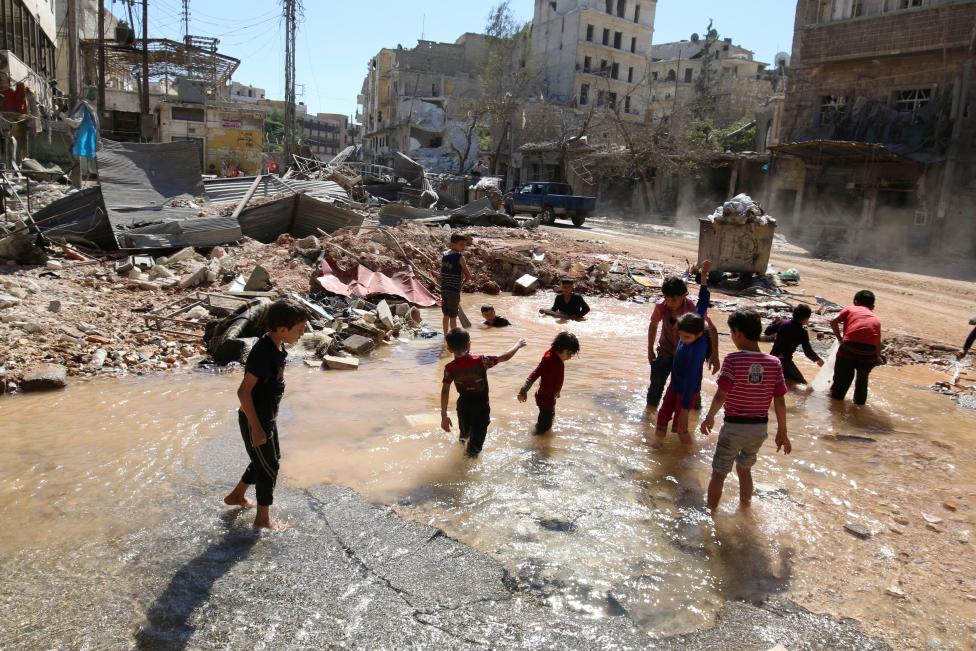 أطفال يسبحون في مياه تجمعت بحفرة تشكلت جرّاء المعارك في حلب