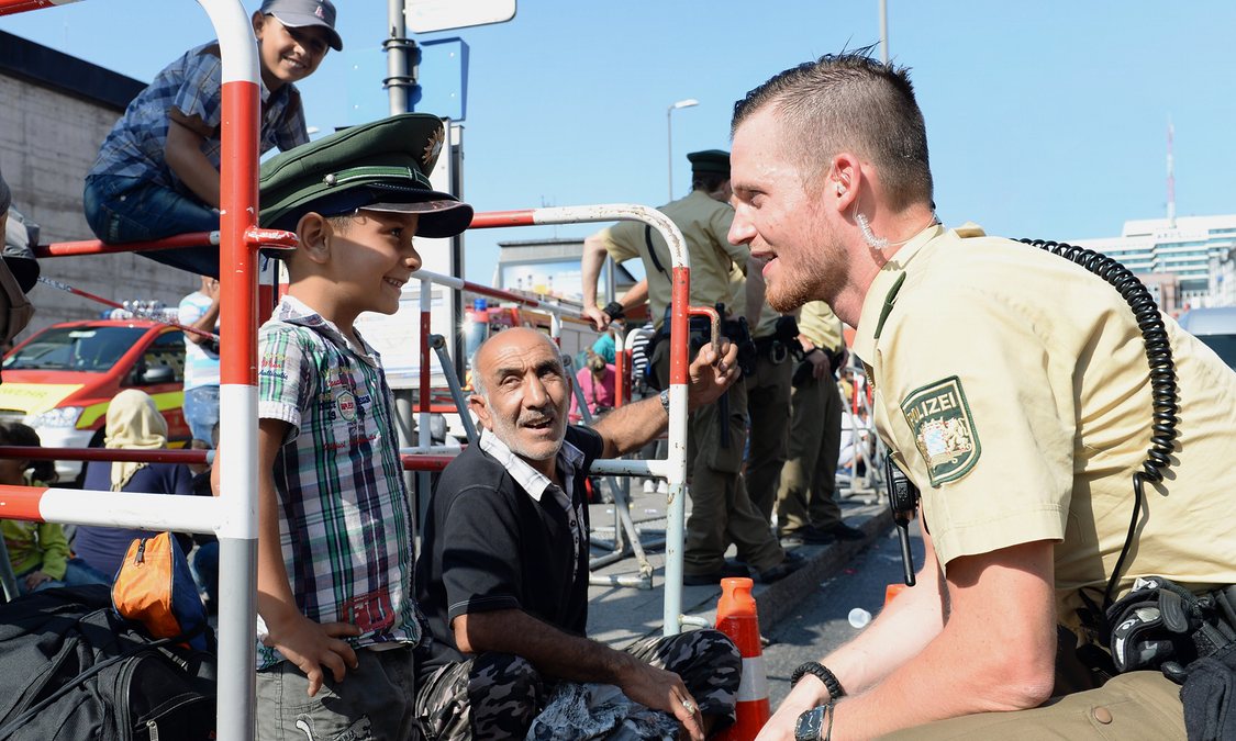 شرطي ألماني يداعب طفل سوري لاجئ في برلين