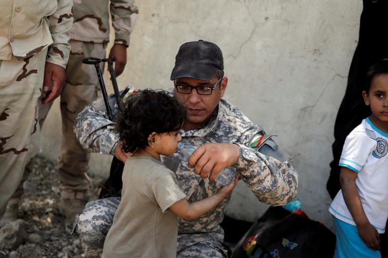 جندي عراقي يروي أحد الأطفال العطشى المدنيين الناجيين من داعش في الموصل القديمة