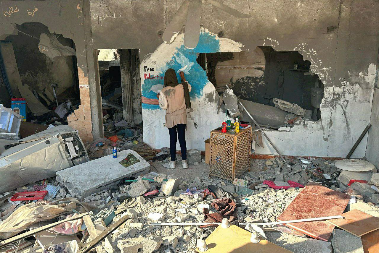 فلسطينية تجسد معاناة شعبها برسم لوحات على ركام المنازل المدمرة