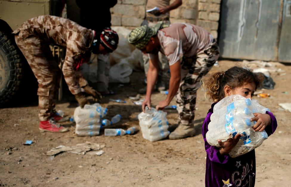 عناصر من الحشد الشعبي يوزعون الماء على الأطفال جنوبي الموصل