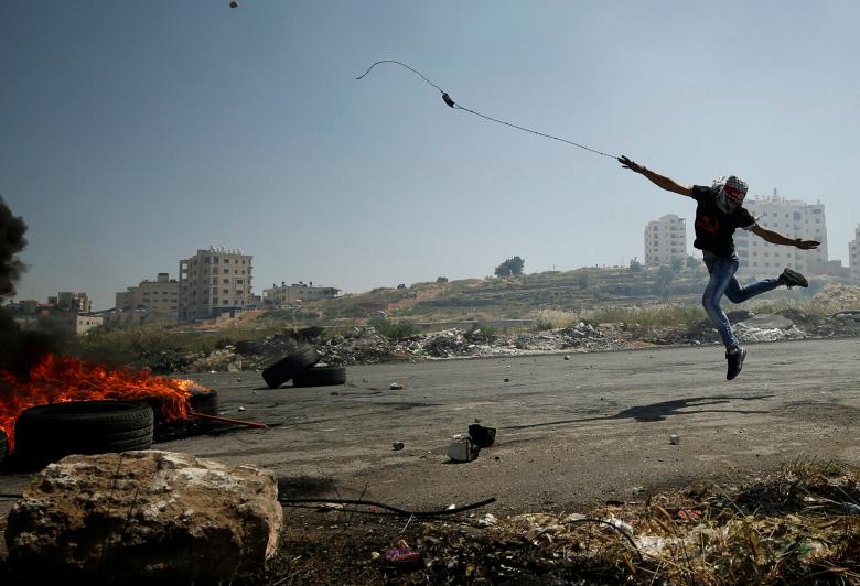 فلسطيني يقذف الحجارة على قوات الاحتلال قرب مستوطنة في رام الله 