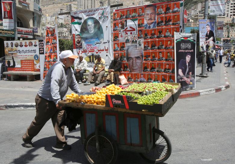 بائع فلسطيني يرفع صور الأسرى المضربين في مدينة نابلس بالضفة الغربية 